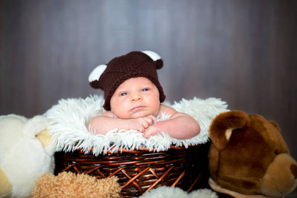 istock Cute newborn baby boy in basket with teddy bear hat, looking at camera 845995436