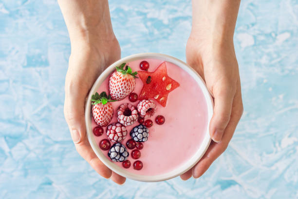 frauenhand hält rosa joghurt smoothie schüssel mit beeren und wassermelone - strawberry fruit single object food stock-fotos und bilder