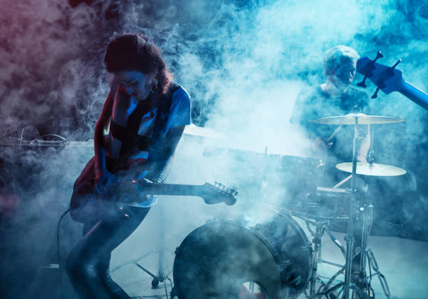 Girl-guitar player plays solo. Rock concert. Scene. Smoke Stage light.