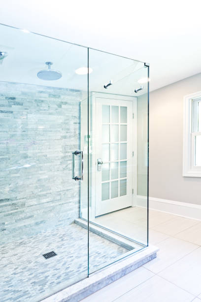 A contemporary modern bathroom design. Glass enclosed shower stall with marble tiles. A newly remodeled luxury bathroom.