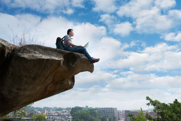 istock Man sitting at the edge of a cliff using laptop 846006422