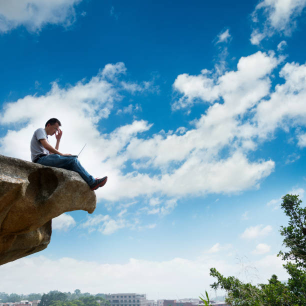 istock Man standing at the edge of a cliff using laptop 846006460