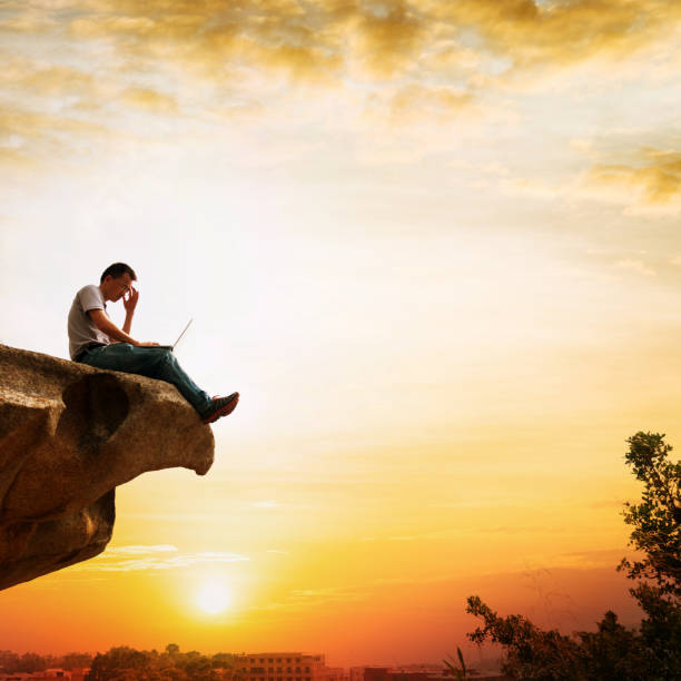 istock Man standing at the edge of a cliff using laptop 846006598