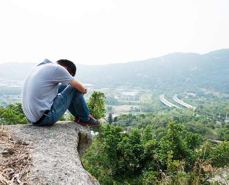 Man sitting at the edge of a cliff and thinking