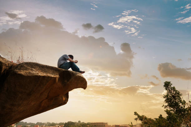 istock Man sitting at the edge of a cliff and thinking 846007154