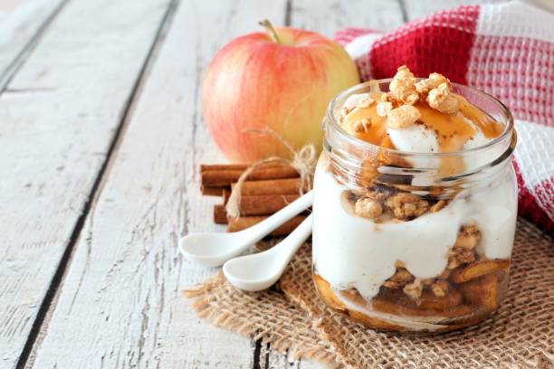 Baked apple parfait in a mason jar on white wood Sweet baked apple parfait in a mason jar on a rustic white wood background parfait stock pictures, royalty-free photos & images