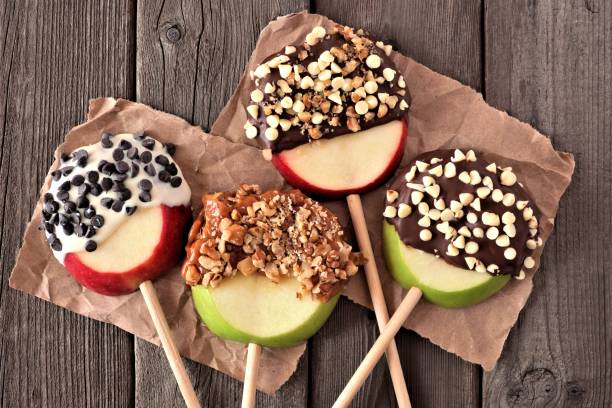 Chocolate and caramel dipped apple rounds, above on rustic wood Mixed chocolate and caramel dipped apple rounds, above view on a rustic wood background green apple slice overhead stock pictures, royalty-free photos & images