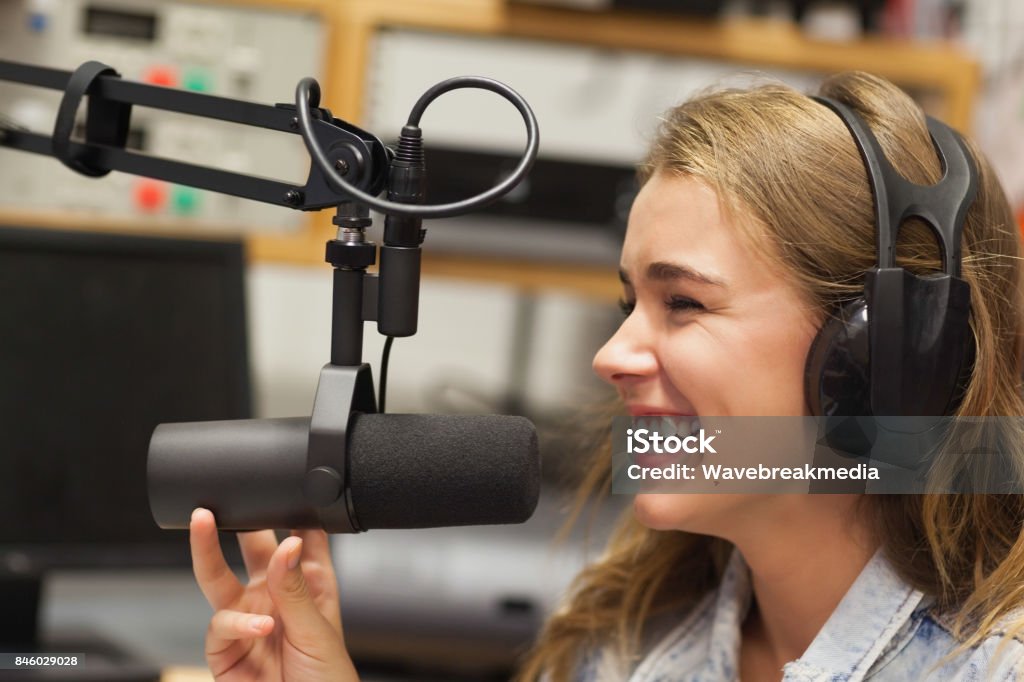Laughing pretty radio host moderating Laughing pretty radio host moderating sitting in studio at college Microphone Stock Photo