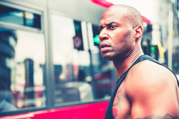 Portrait of a muscular man waiting in front of a bus for it to pass to cross the street.