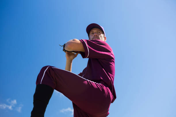 vue faible angle de lancer la balle contre le ciel bleu de baseball - low angle view photos et images de collection