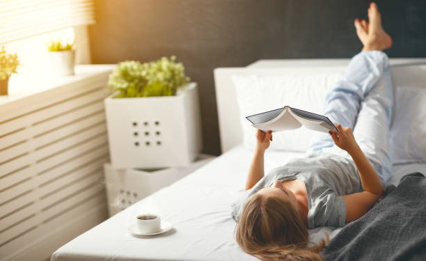 happy young woman reads  book and drinks coffee in bed - foods and drinks clothing garment household equipment imagens e fotografias de stock