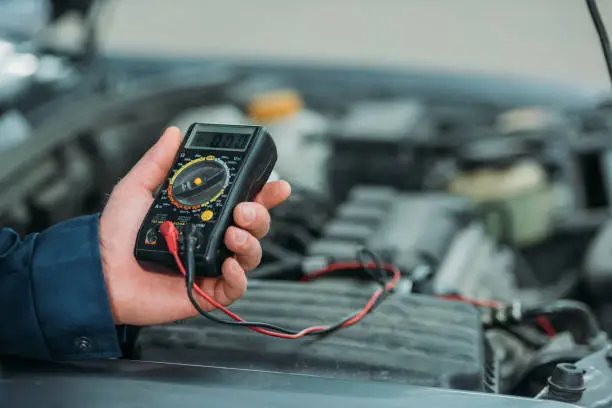 Cropped shot of automechanic using a digital multimeter in a service workshop.