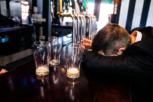 Drunk man with empty glasses in a bar