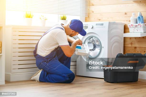 Working Man Plumber Repairs Washing Machine In Laundry Stock Photo - Download Image Now