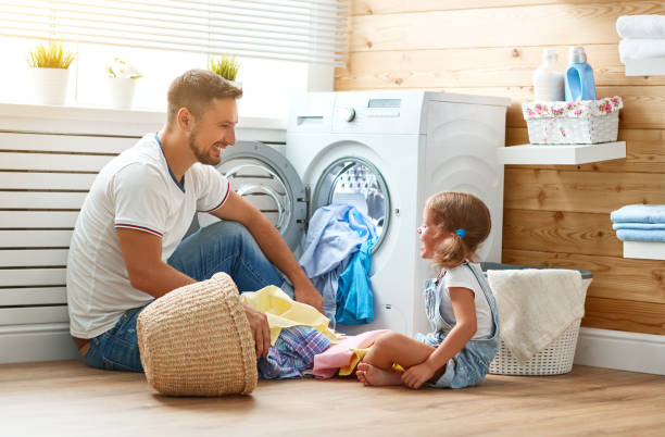 Happy family man father householder and child   in laundry with washing machine Happy family man father  householder and child daughter in laundry with washing machine father housework stock pictures, royalty-free photos & images