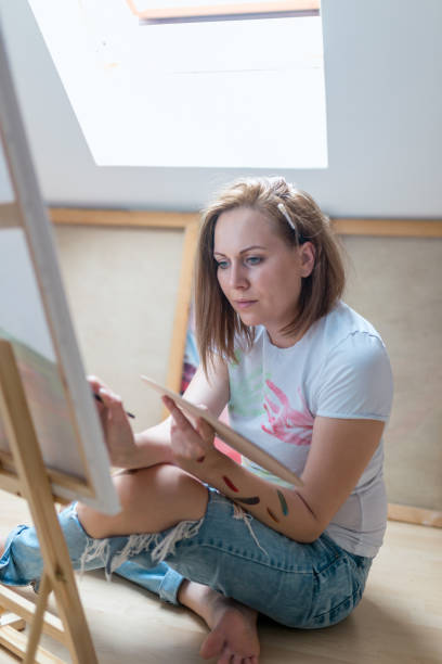 istock Happy young woman paints on canvas 846044770
