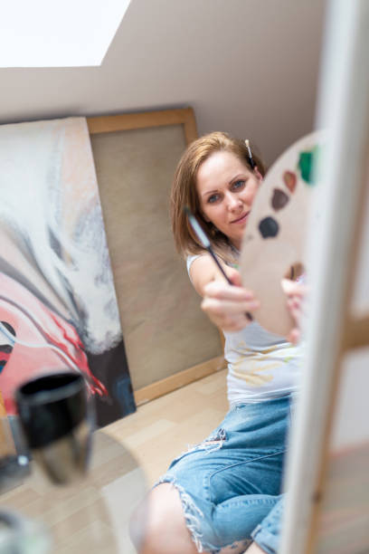 istock Happy young woman paints on canvas 846047270