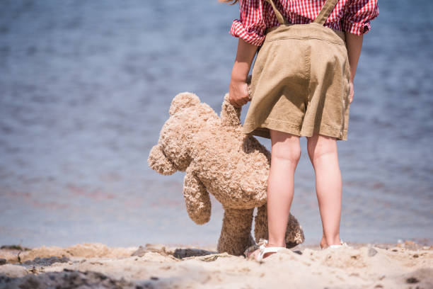 istock child with teddy bear at seashore 846047714