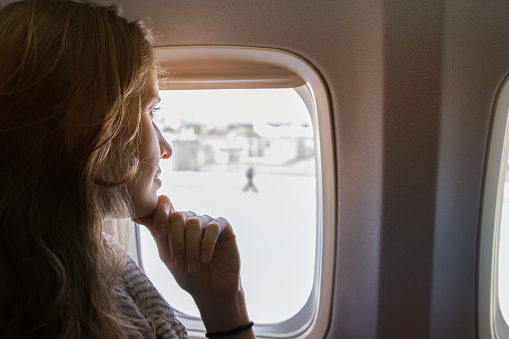 Portrait the beautiful woman on the plane looking out of the window