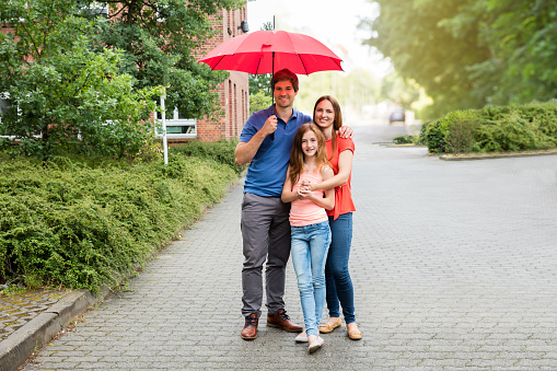 Portrait Of A Young Couple With Their Daughter Holding Umbrella