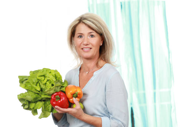 donna felice matura con insalata e paprika - mature women beautiful senior women menopause foto e immagini stock