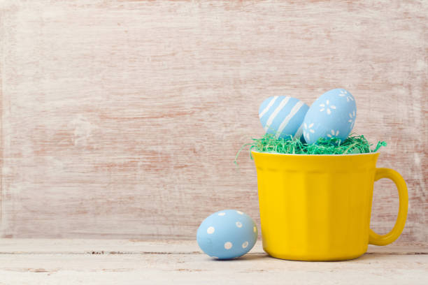 Easter holiday concept with egg decoration in yellow cup on wooden table