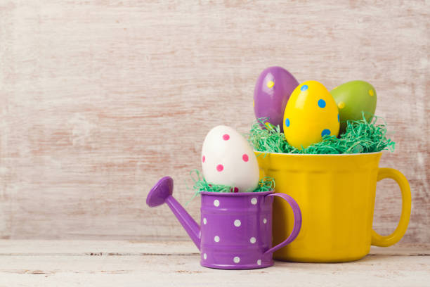 istock Easter holiday concept with egg decoration in yellow cup and watering can over rustic background 846055332