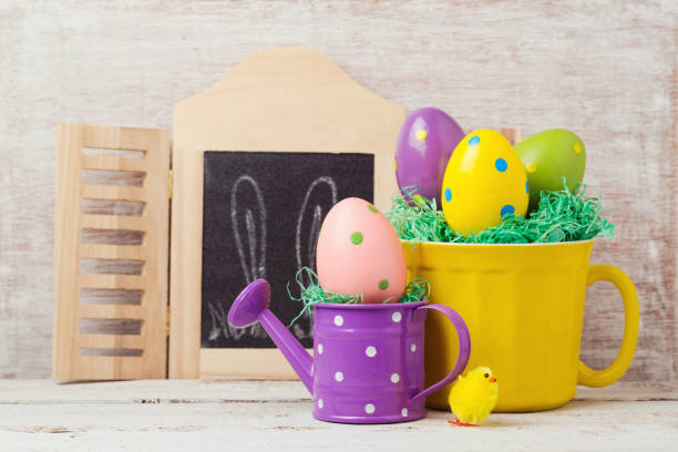 istock Easter holiday concept with painted eggs decoration, cup and watering can over rustic background 846055344