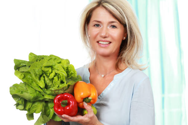 donna felice matura con insalata e paprika - mature women beautiful senior women menopause foto e immagini stock