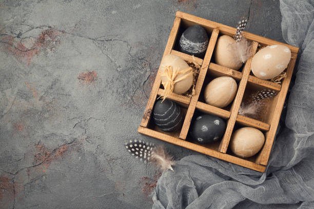 Easter holiday concept with egg decoration in wooden box over blackboard background. View from above