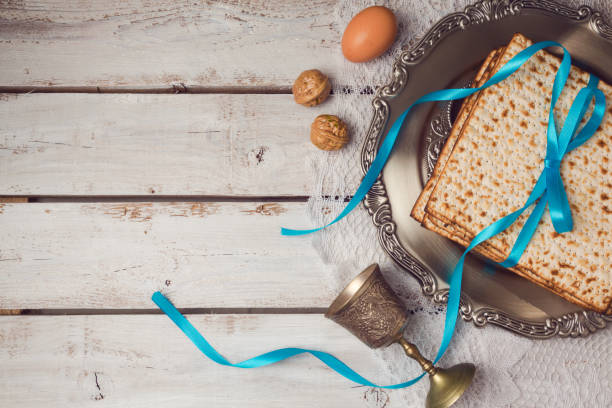 concepto de pascua día de fiesta judío con matzá, placa de seder y copa de vino sobre fondo blanco de mesa. vista desde arriba. endecha plana - seder passover seder plate matzo fotografías e imágenes de stock