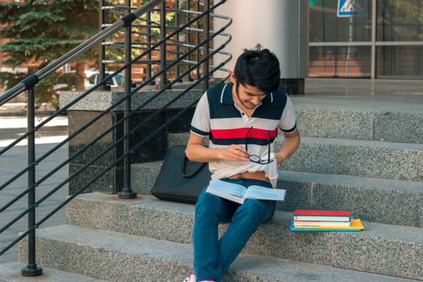 istock young cute student sits on the stairs and reads books 846058370