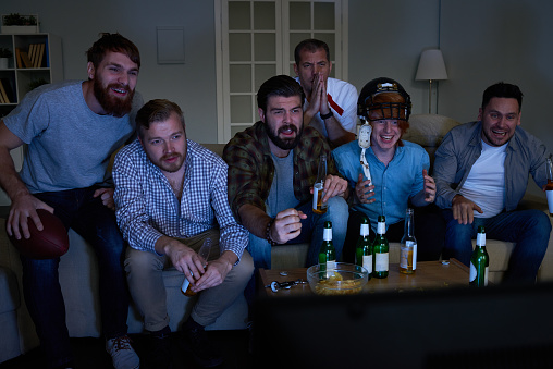 Emotional male friends concentrated on rugby match while watching broadcasting at home
