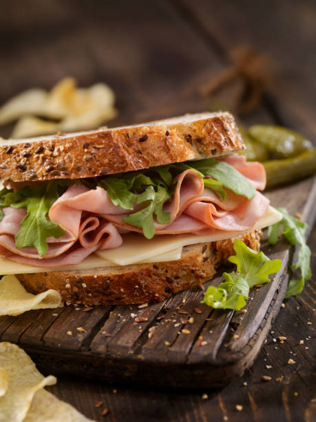 schinken, schweizer und rucola sandwich - cheese focus on foreground on top of portion stock-fotos und bilder