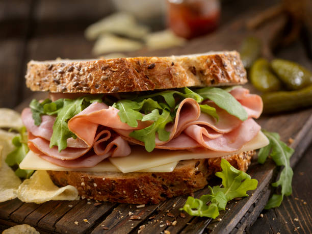 Ham, Swiss and Arugula Sandwich Ham, Swiss and Arugula Sandwich on Whole Grain Artisan Bread cold cuts meat photos stock pictures, royalty-free photos & images