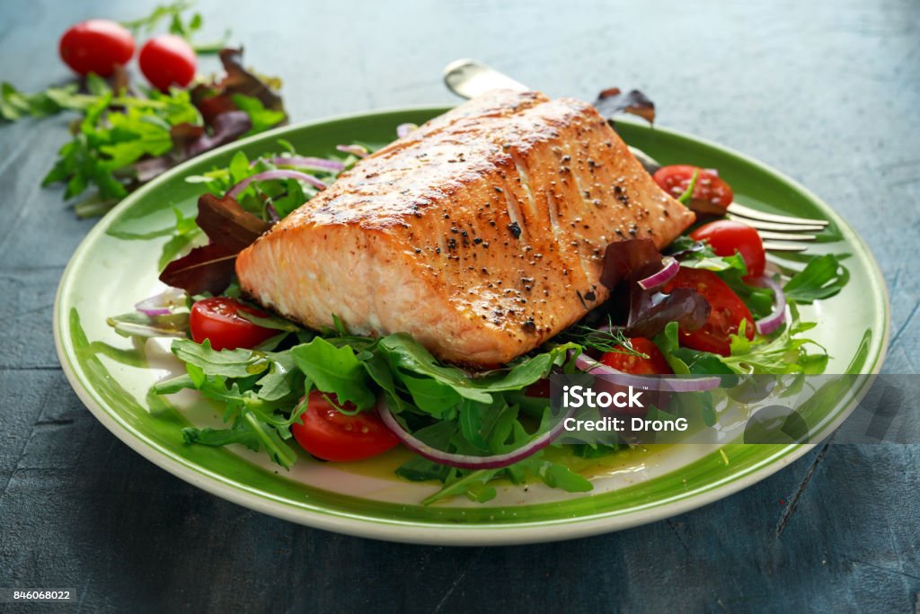 Darne de saumon cuit au four avec tomates, oignons, mélange de vert feuilles de salade dans une assiette. alimentation saine - Photo de Saumon - Animal libre de droits