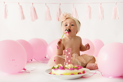 Little girl, one year old, smashing the cake during her birthday party.