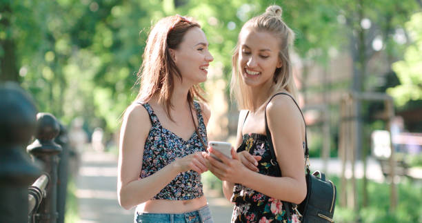 Two teenage girls using mobile phone in a city park. stock photo