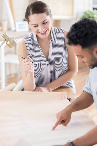istock Male architect reviews blueprint with colleague 846100220