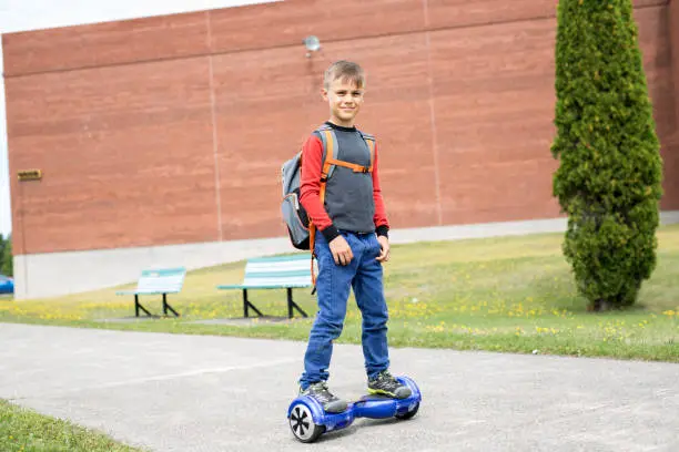 A Little boy riding a mini segway. He's good at it. He likes it.