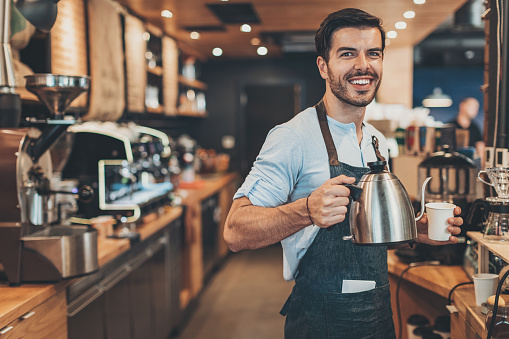Smiling male barista working in a coffee shop