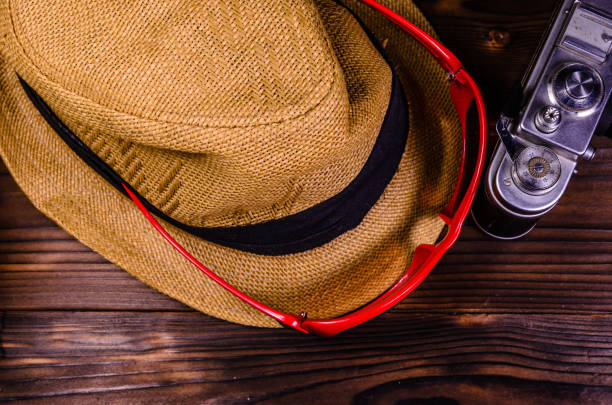 Old rangefinder camera, sunglasses and hat on wooden table