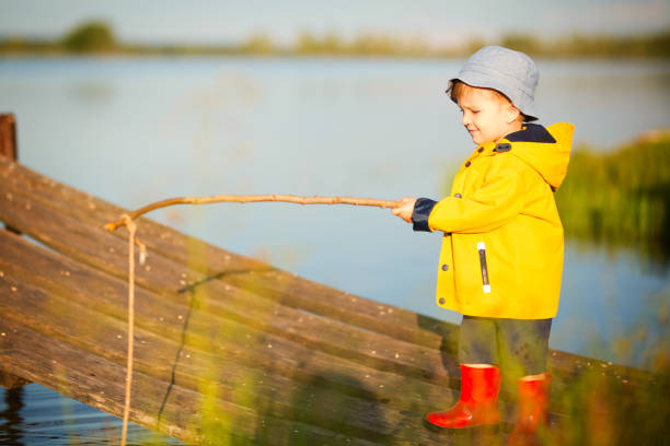 giovane bambino che pesca dal molo di legno - sweden fishing child little boys foto e immagini stock