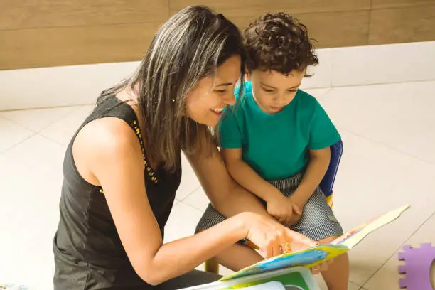 Mother teaching her son, reading a children's book and having fun.