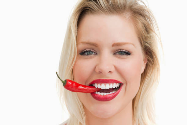 istock Happy woman biting a red chili while standing 846134826