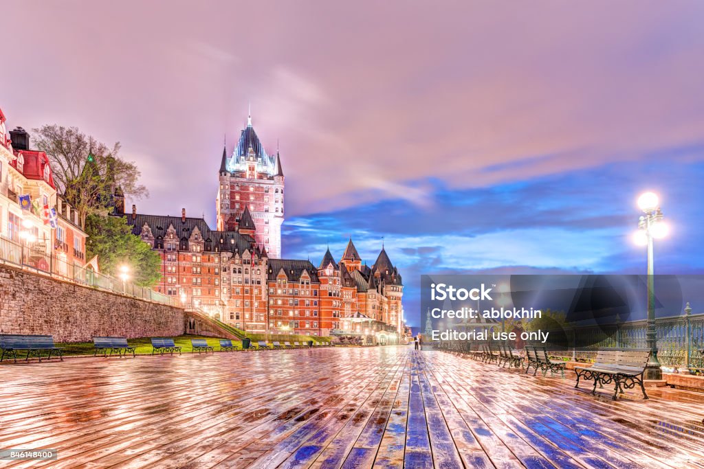 Closeup of old town ground level view of wet dufferin terrace boardwalk at night with Chateau Frontenac, purple clouds, city lights, lamps, lanterns and people Quebec City: Closeup of old town ground level view of wet dufferin terrace boardwalk at night with Chateau Frontenac, purple clouds, city lights, lamps, lanterns and people Architecture Stock Photo