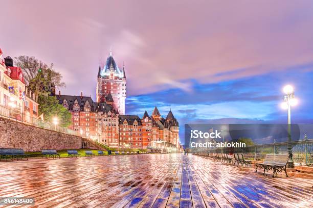 Closeup Of Old Town Ground Level View Of Wet Dufferin Terrace Boardwalk At Night With Chateau Frontenac Purple Clouds City Lights Lamps Lanterns And People Stock Photo - Download Image Now