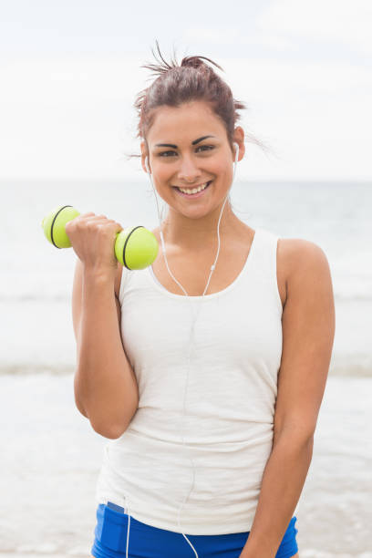 istock Cheerful smiling woman lifting dumbbells standing on beach 846155152