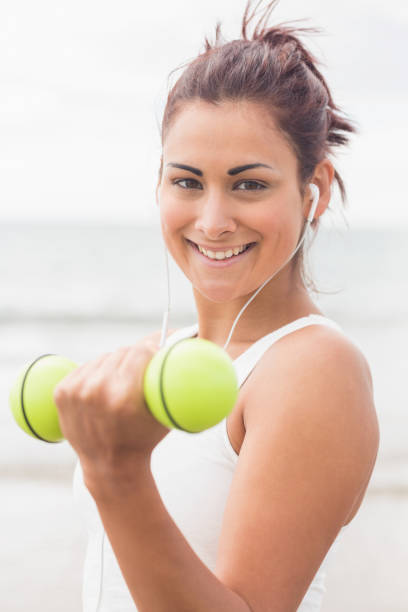 istock Cute smiling woman lifting dumbbells on the beach 846155224