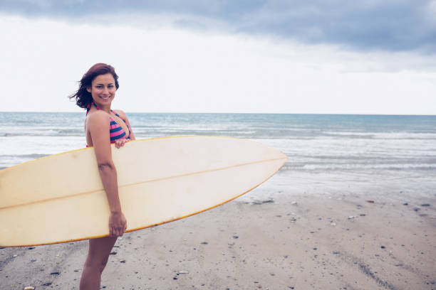 istock Smiling woman carrying surfboard on the beach 846155474